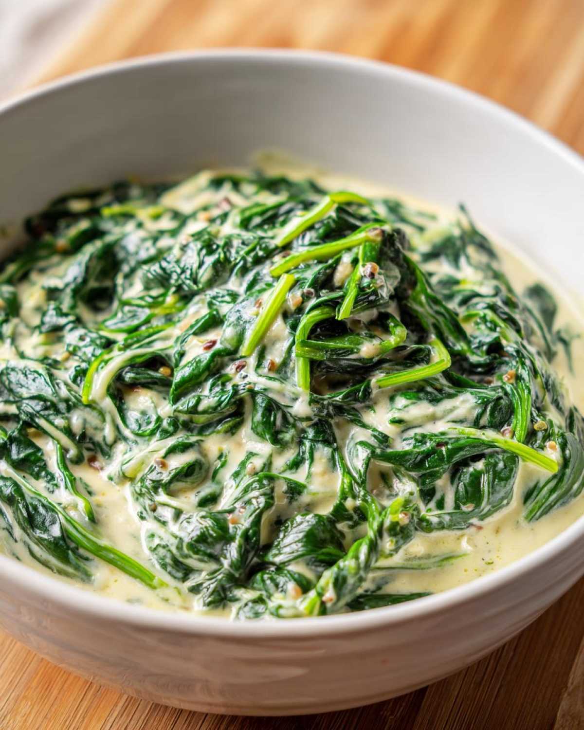 A close-up of vibrant green spinach coated in a creamy white sauce, showcasing the amazing creamed spinach recipe.