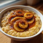 A close-up of creamy banana oatmeal topped with caramelized banana slices and cinnamon syrup.