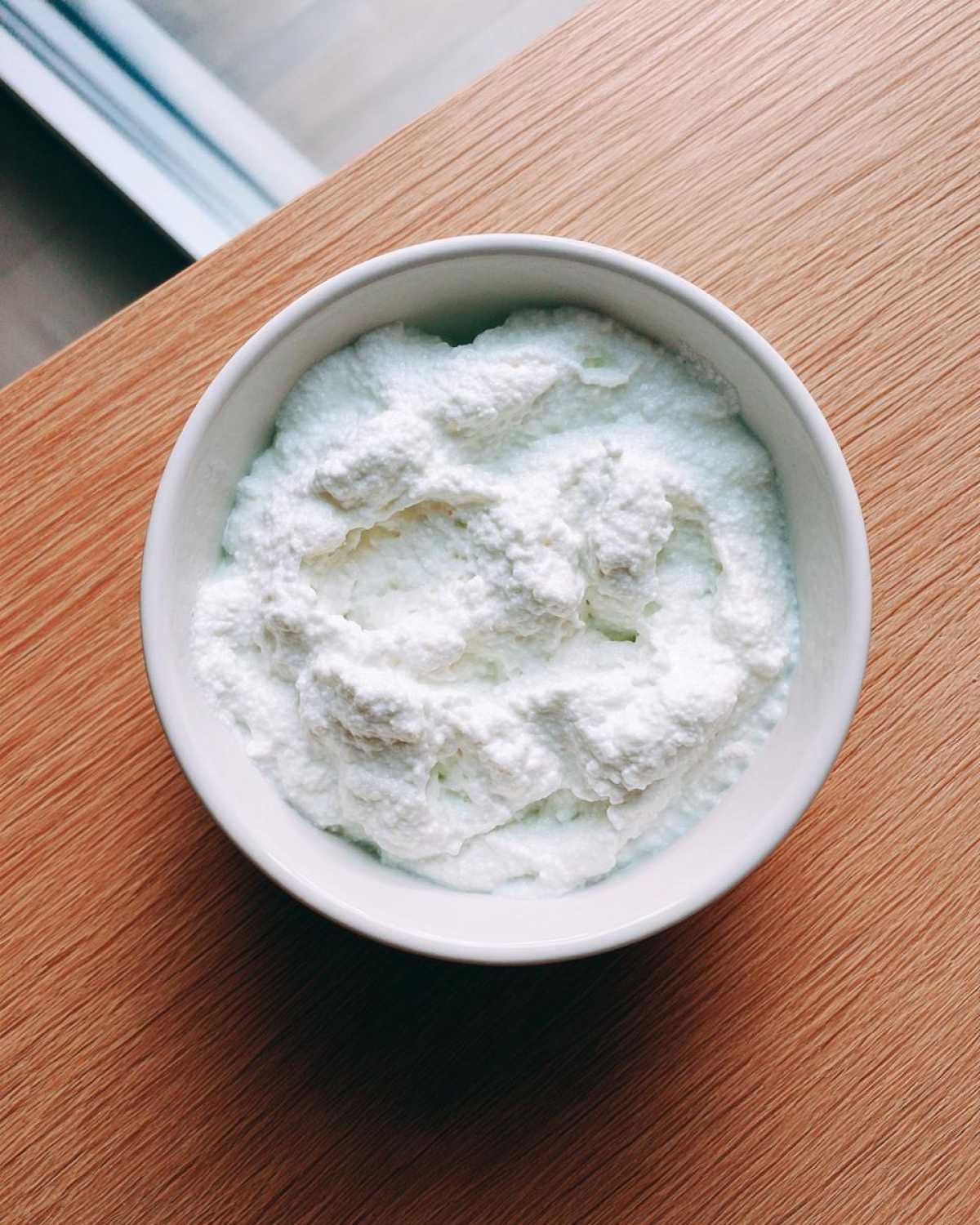 Overhead view of a white bowl filled with a thick, white, creamy mixture, likely the base for coconut chia pudding.