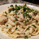 Close-up of creamy chicken fettuccine alfredo pasta topped with fresh parsley.