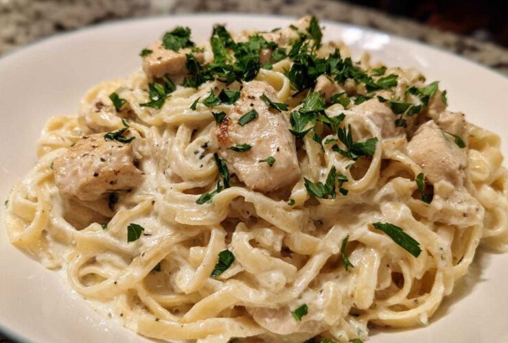 Close-up of creamy chicken fettuccine alfredo pasta topped with fresh parsley.