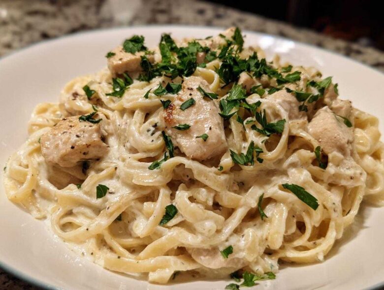 Close-up of creamy chicken fettuccine alfredo pasta topped with fresh parsley.