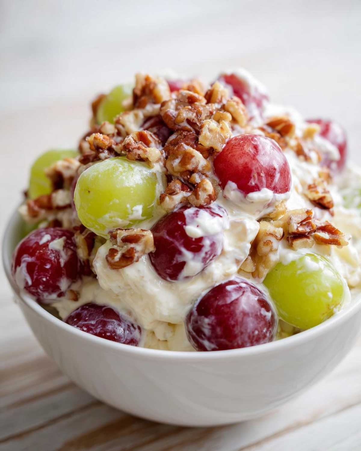 Close-up of creamy chicken salad chick grape salad topped with red and green grapes and chopped pecans.