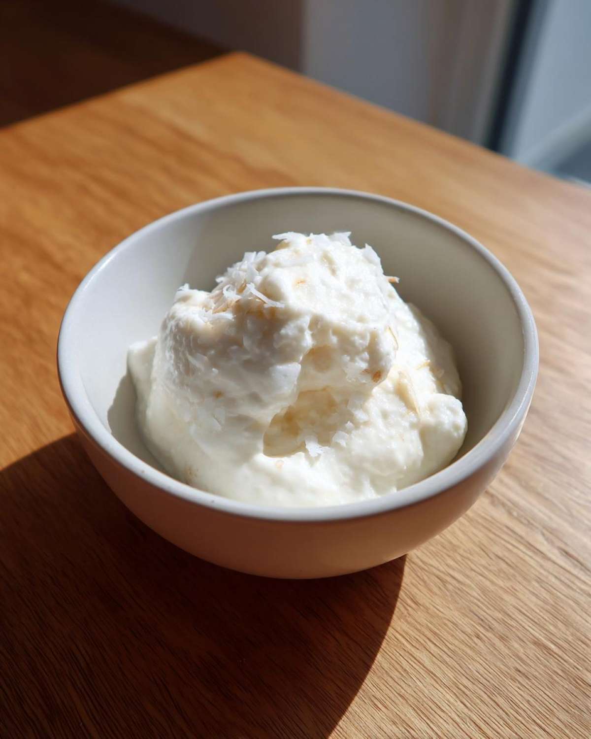 A serving of creamy white coconut chia pudding topped with toasted coconut flakes in a small bowl.