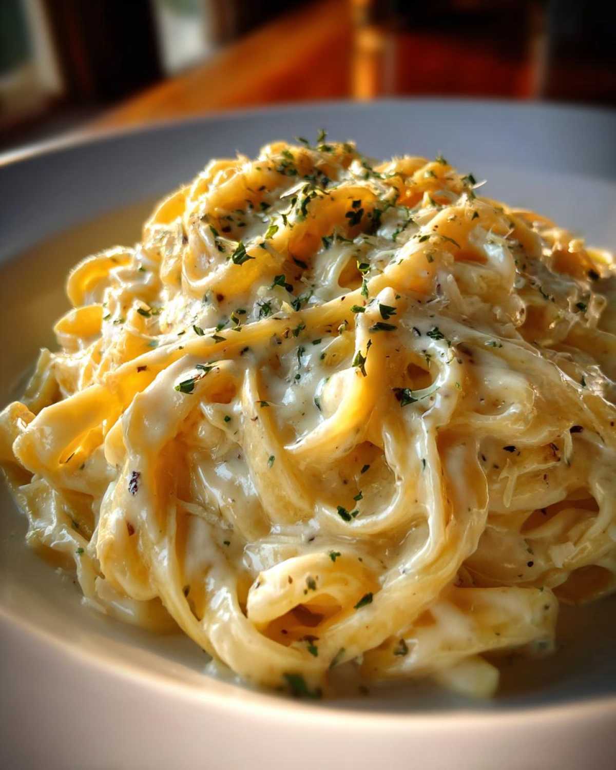 Close-up of fettuccine pasta coated in rich, creamy Olive Garden Alfredo Sauce and topped with parsley.
