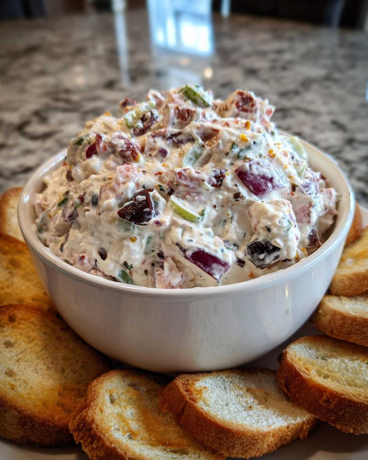A white bowl filled with creamy hoagie dip, surrounded by toasted bread slices, ready for serving.