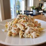 A serving of creamy Tuna pasta salad made with fusilli pasta, tuna, and chopped vegetables, garnished with parsley.