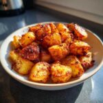 A bowl filled with perfectly crispy, golden brown breakfast potatoes, catching the sunlight.