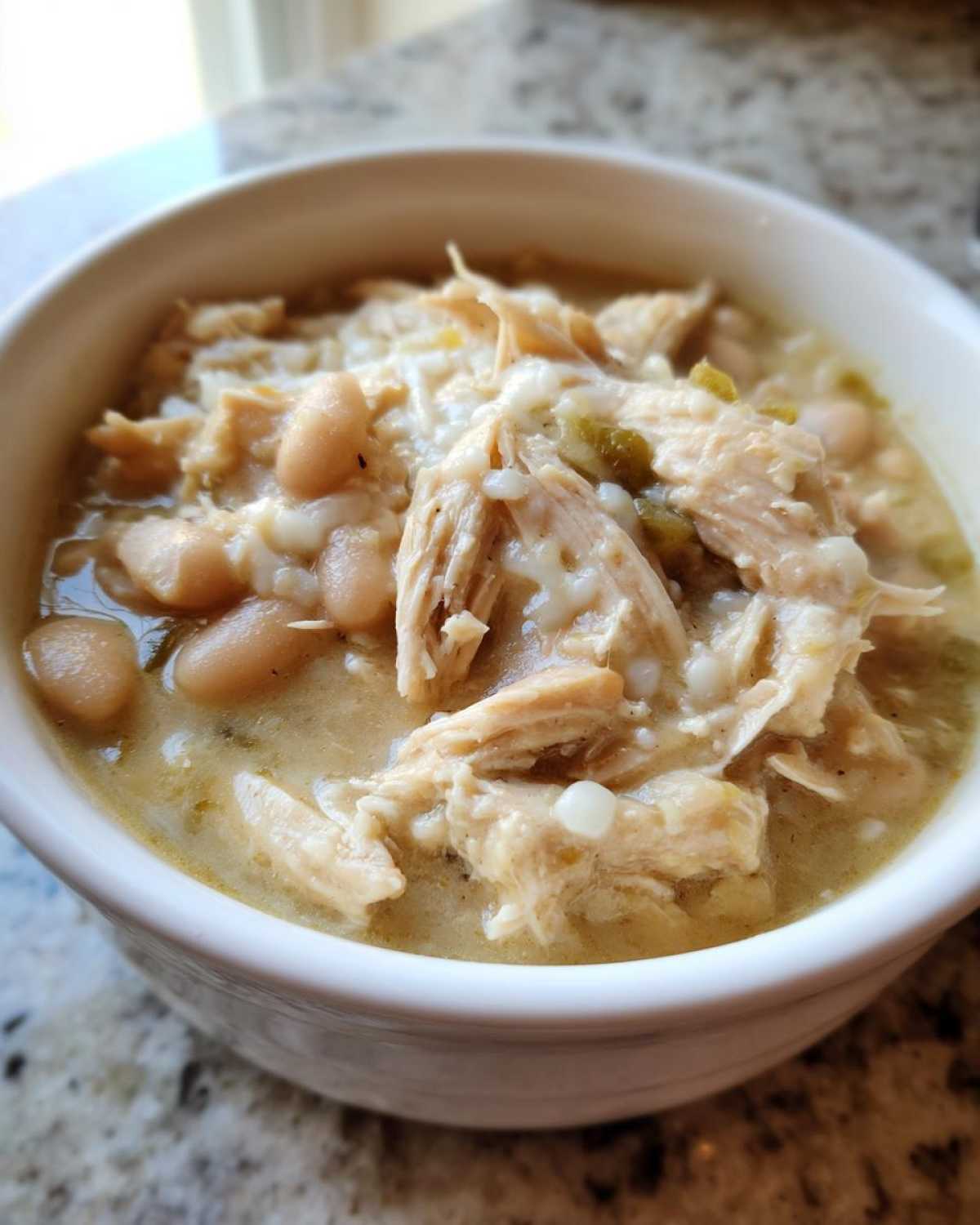 Close-up of a bowl filled with creamy crockpot white chicken chili featuring shredded chicken and white beans.