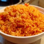 Close-up of a white bowl filled with vibrant orange, fluffy spanish rice, ready to serve.