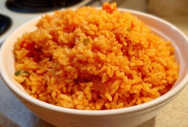 Close-up of a white bowl filled with vibrant orange, fluffy spanish rice, ready to serve.