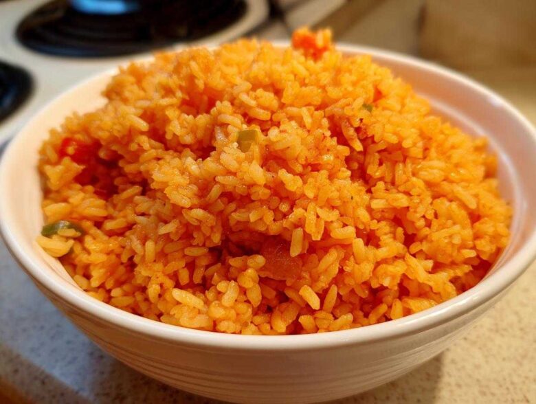 Close-up of a white bowl filled with vibrant orange, fluffy spanish rice, ready to serve.