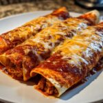 Three rolled easy chicken enchiladas covered in rich red sauce and melted white and orange cheese on a white plate.