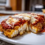 Close-up of a cross-section of Easy Chicken Parmesan showing crispy breading, white chicken meat, marinara sauce, and melted mozzarella cheese.