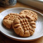 Three classic Easy Peanut Butter Cookies with criss-cross fork marks served on a light ceramic plate.