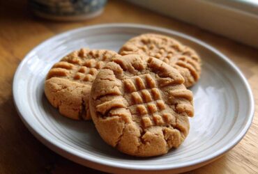 Three classic Easy Peanut Butter Cookies with criss-cross fork marks served on a light ceramic plate.