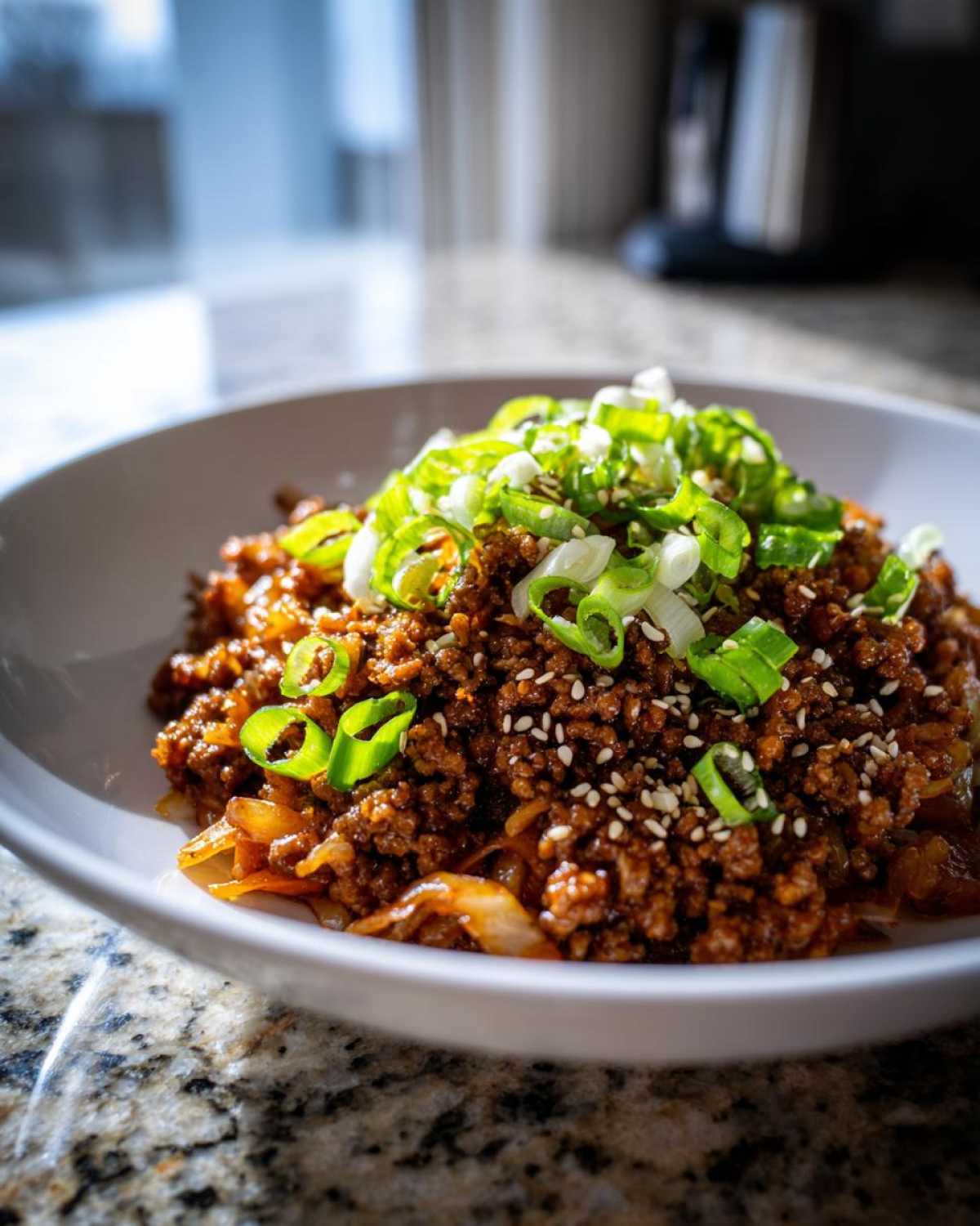 Close-up of a savory Egg Roll in a Bowl made with ground meat, topped generously with sliced green onions and sesame seeds.