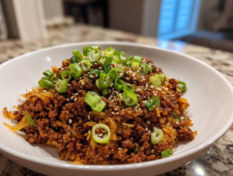A close-up of a hearty serving of Egg Roll in a Bowl topped with fresh green onions and sesame seeds.