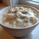A close-up of thick, creamy homemade cream of chicken soup topped with pepper in a white ribbed bowl.