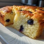 Close-up of a fluffy slice of blueberry sheet pan pancakes showing the golden crust and moist interior.