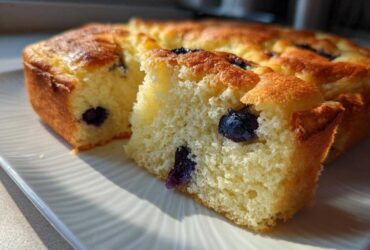Close-up of a fluffy slice of blueberry sheet pan pancakes showing the golden crust and moist interior.