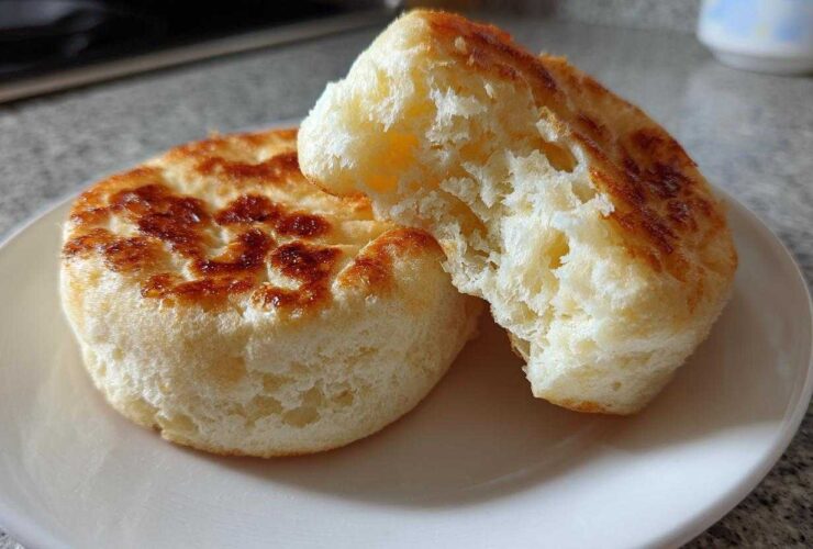 Close-up of a fluffy, toasted english muffin split in half showing its airy interior texture.