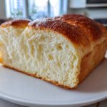 Close-up of a freshly baked japanese milk bread loaf, showing its incredibly soft, fluffy, and white interior crumb.