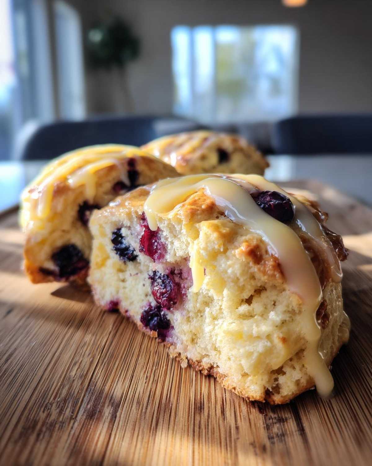 Close-up of a fluffy lemon blueberry scone cut in half, showing blueberries and topped with a thick lemon glaze.