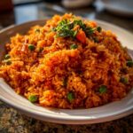 A close-up of a generous serving of vibrant orange Mexican rice recipe, garnished with fresh cilantro, peas, and diced carrots.