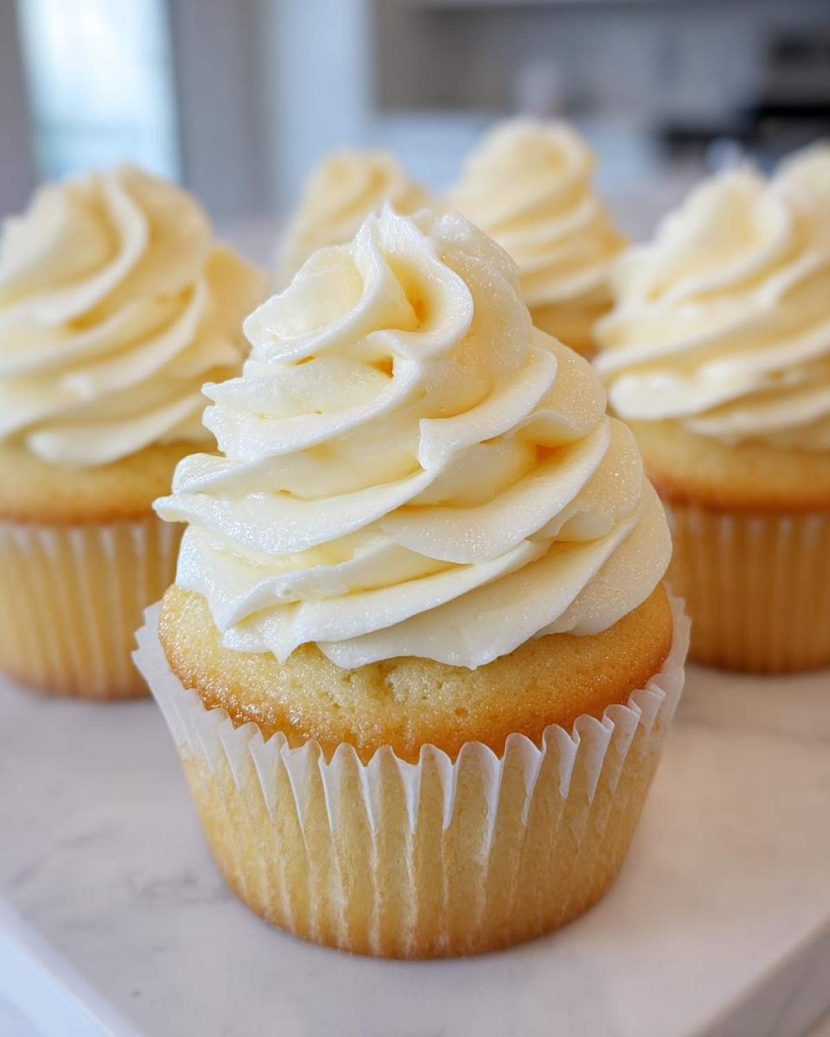 Close-up of a moist vanilla cupcake topped with perfectly swirled, creamy vanilla buttercream frosting.