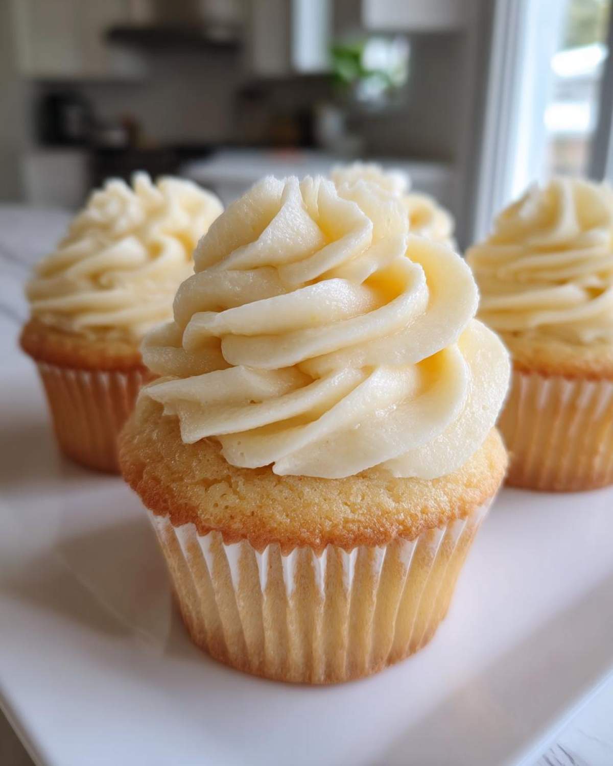 Close-up of a moist vanilla cupcake topped with a swirl of creamy vanilla frosting. Perfect for amazing vanilla cupcakes.