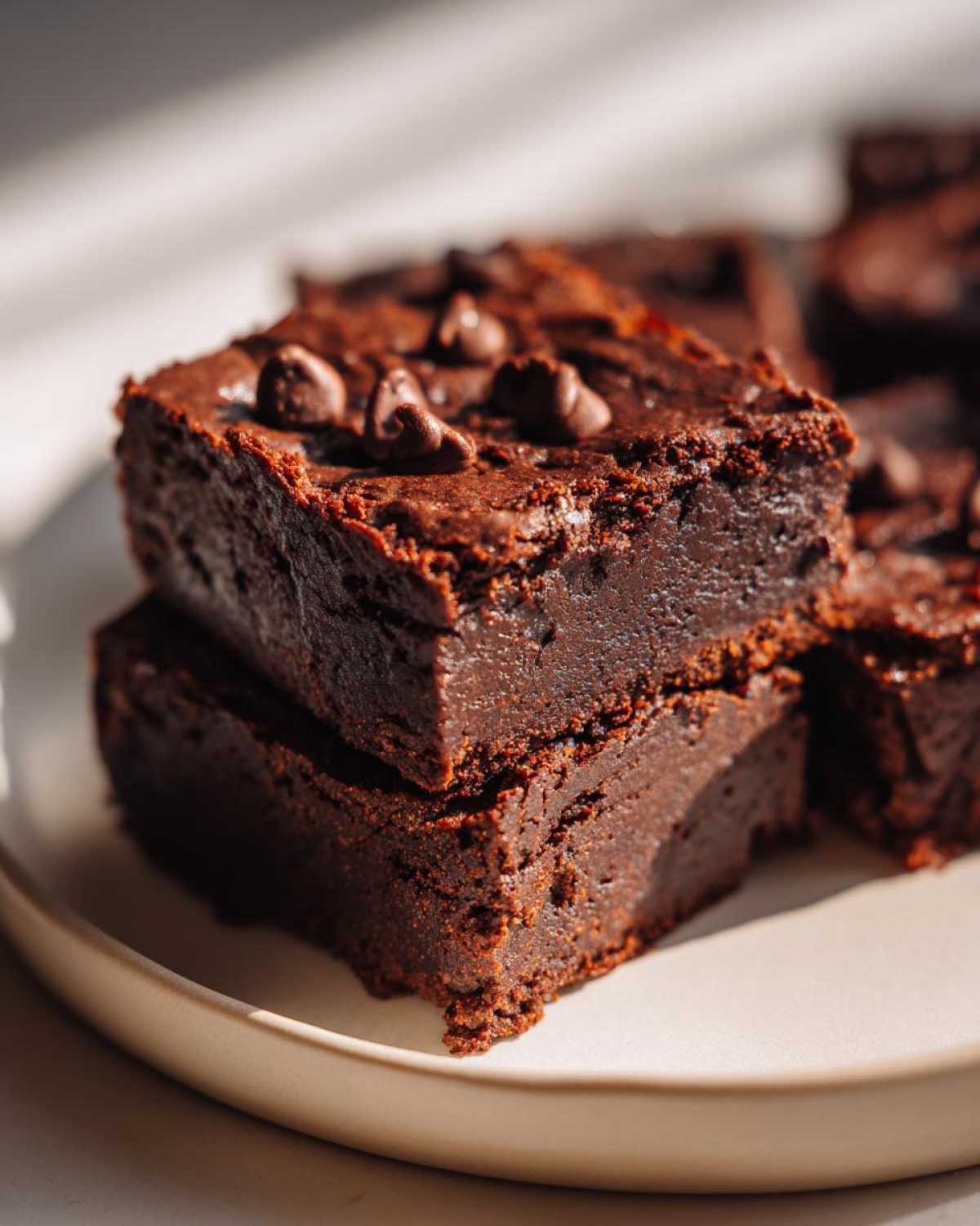Close-up of two stacked, fudgy sweet potato brownies topped with chocolate chips.