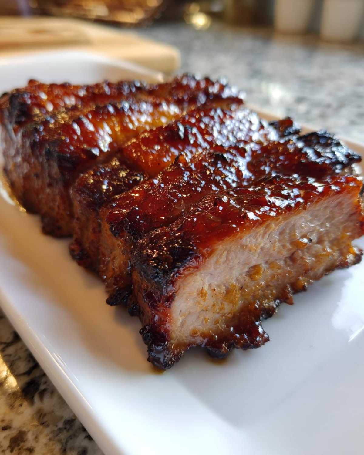 Close-up of three thick, glazed pieces of pork steak recipe, showing a rich, dark, caramelized exterior.
