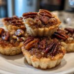 A stack of gooey pecan pie cookies topped with whole pecans, ready to eat.