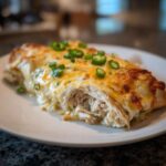 Close-up of a cheesy green chile chicken enchiladas, showing shredded chicken filling and sliced jalapeños.