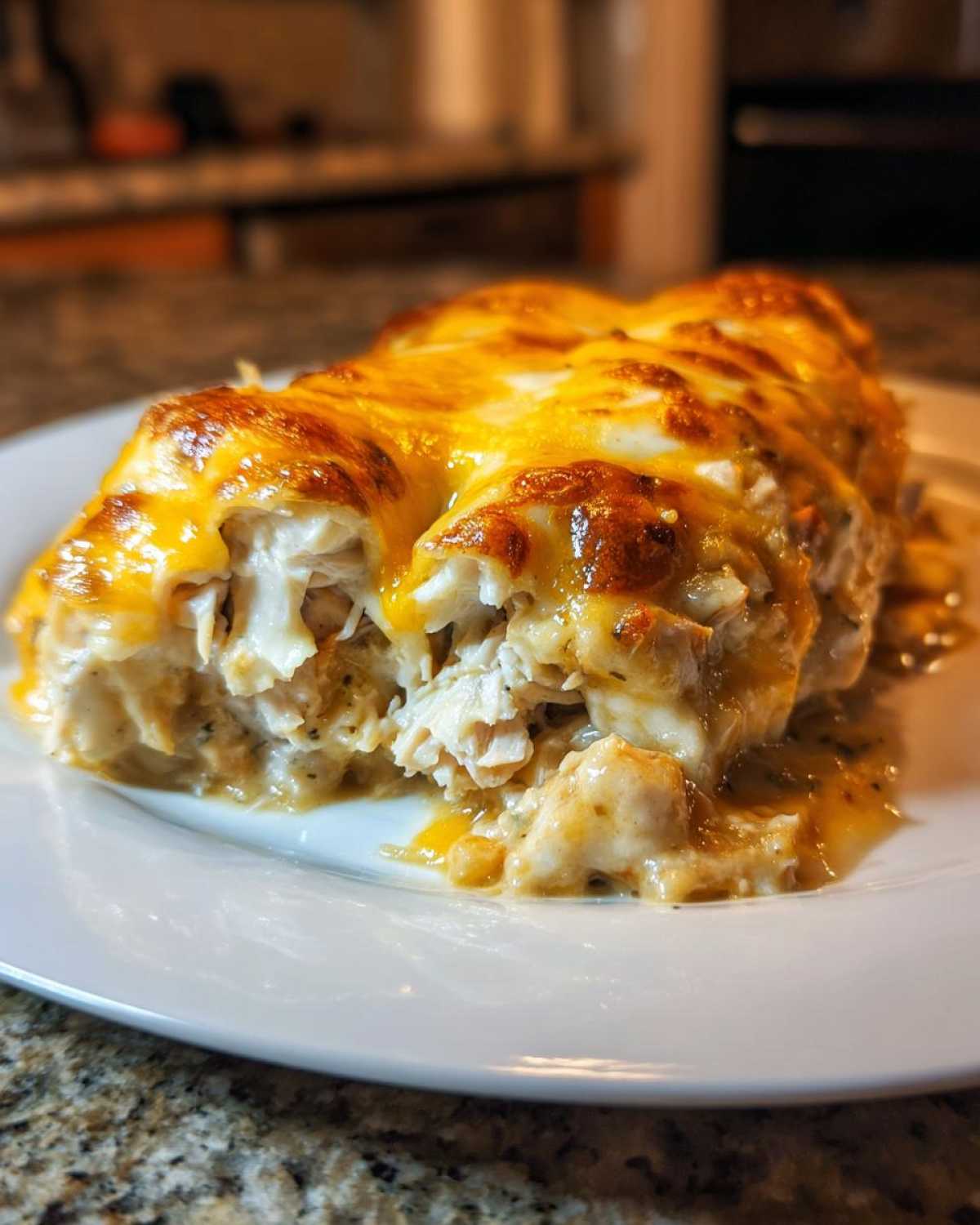 A close-up of a serving of green chile chicken enchiladas smothered in melted, bubbly cheese.