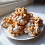 A stack of gooey, peanut butter and marshmallow avalanche cookies piled high on a white plate.