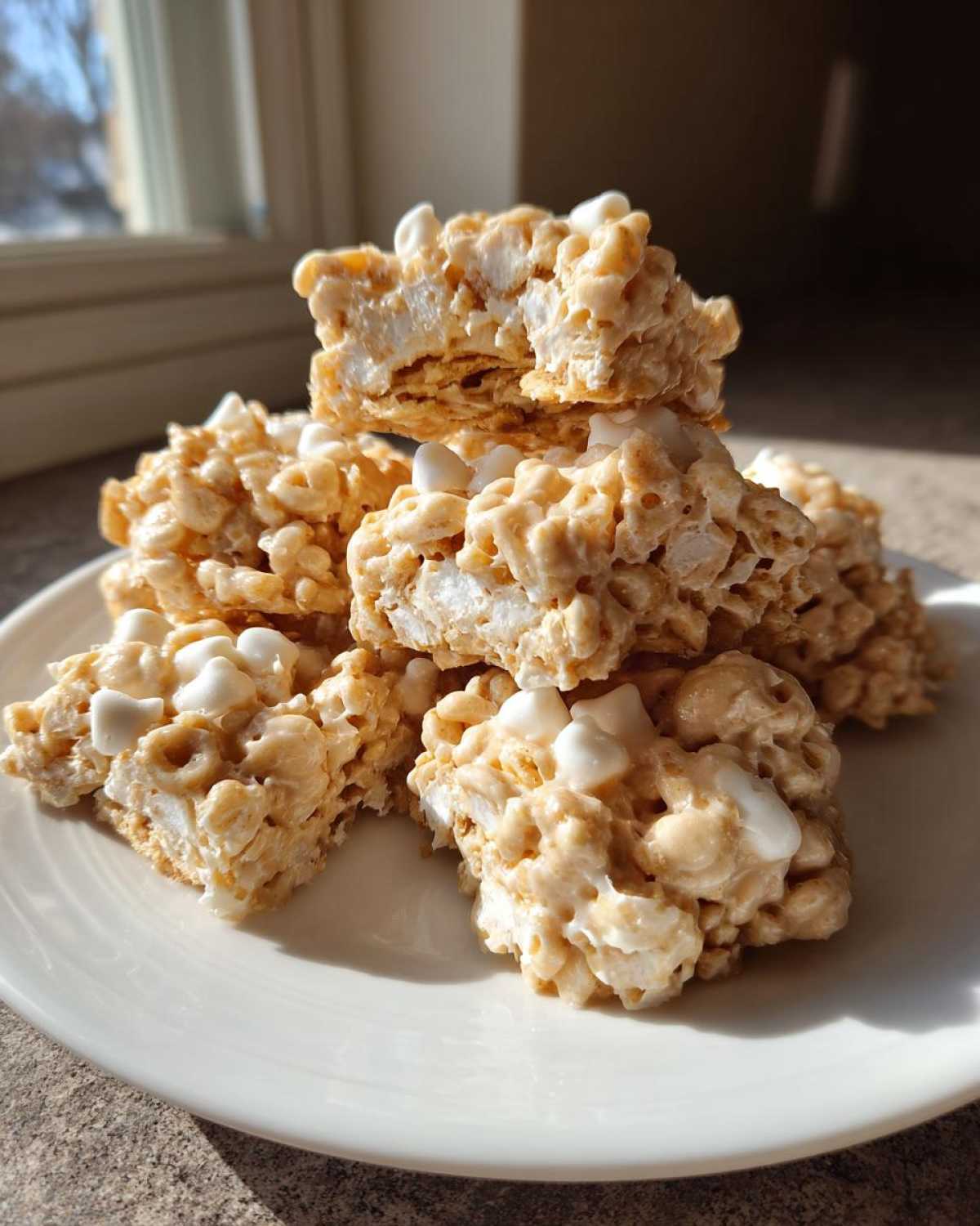 A stack of freshly made avalanche cookies, featuring a chewy texture and visible mini marshmallows, served on a white plate.