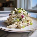 A mound of creamy honey mustard chicken salad mixed with celery and red onion, topped with fresh chives.