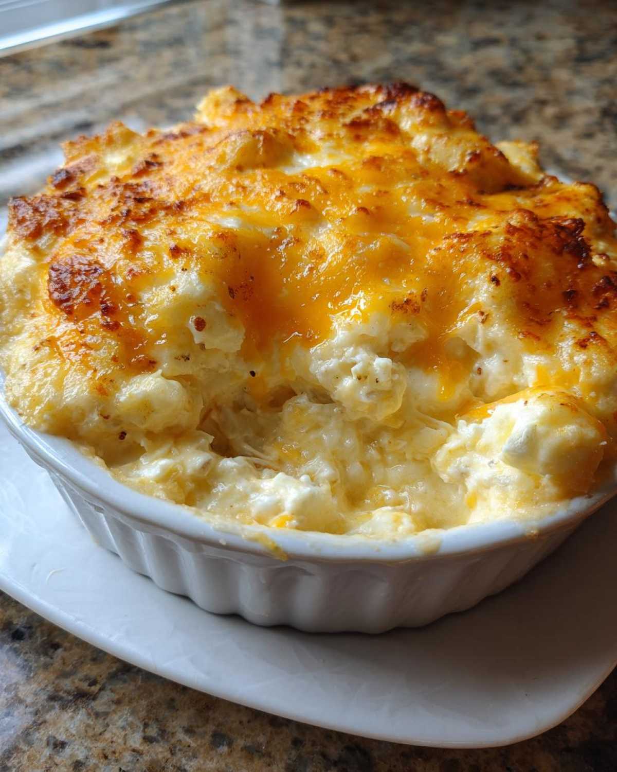 Close-up of a bubbling, cheesy hot crab dip baked to golden perfection in a white ramekin.