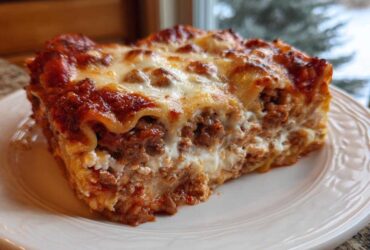 Close-up of a hearty slice of lasagna with cottage cheese, rich meat sauce, and melted cheese topping.