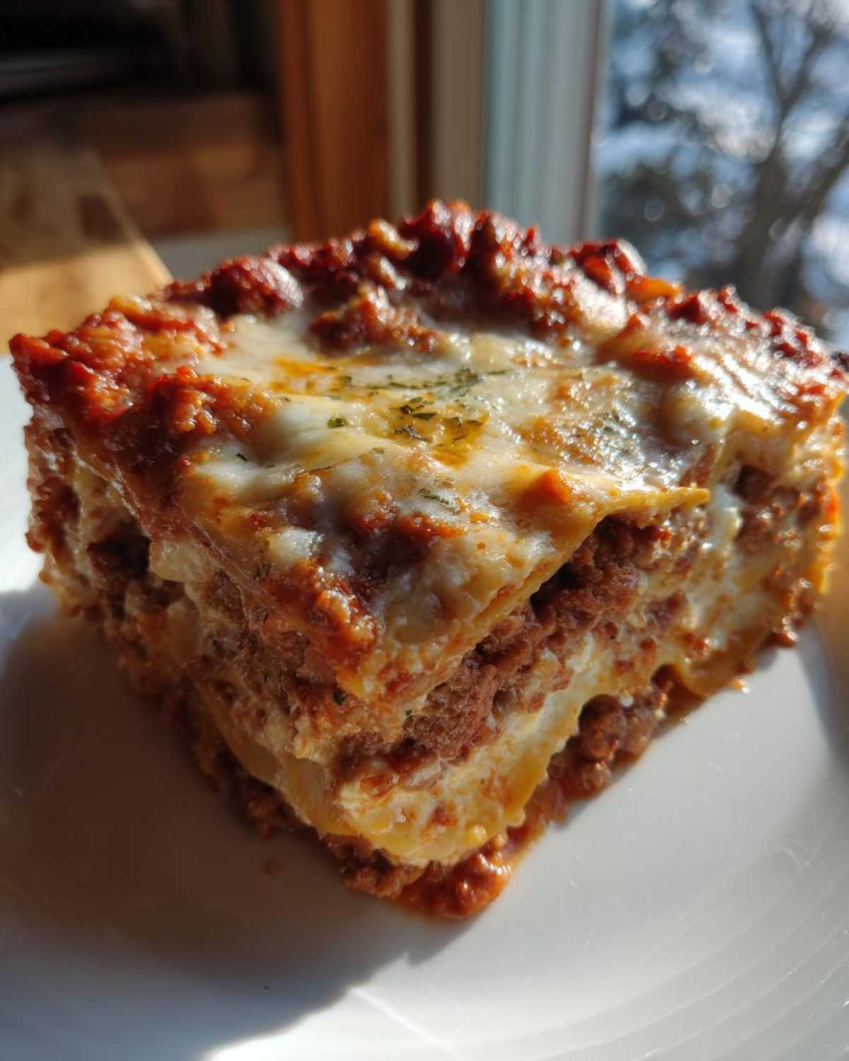 A close-up of a thick, square slice of Lasagna with Cottage Cheese, showing layers of pasta, meat sauce, and melted cheese.