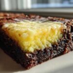 A close-up view of a rich, dark chocolate brownie base topped with a bright yellow, zesty layer of Lemon Brownies.