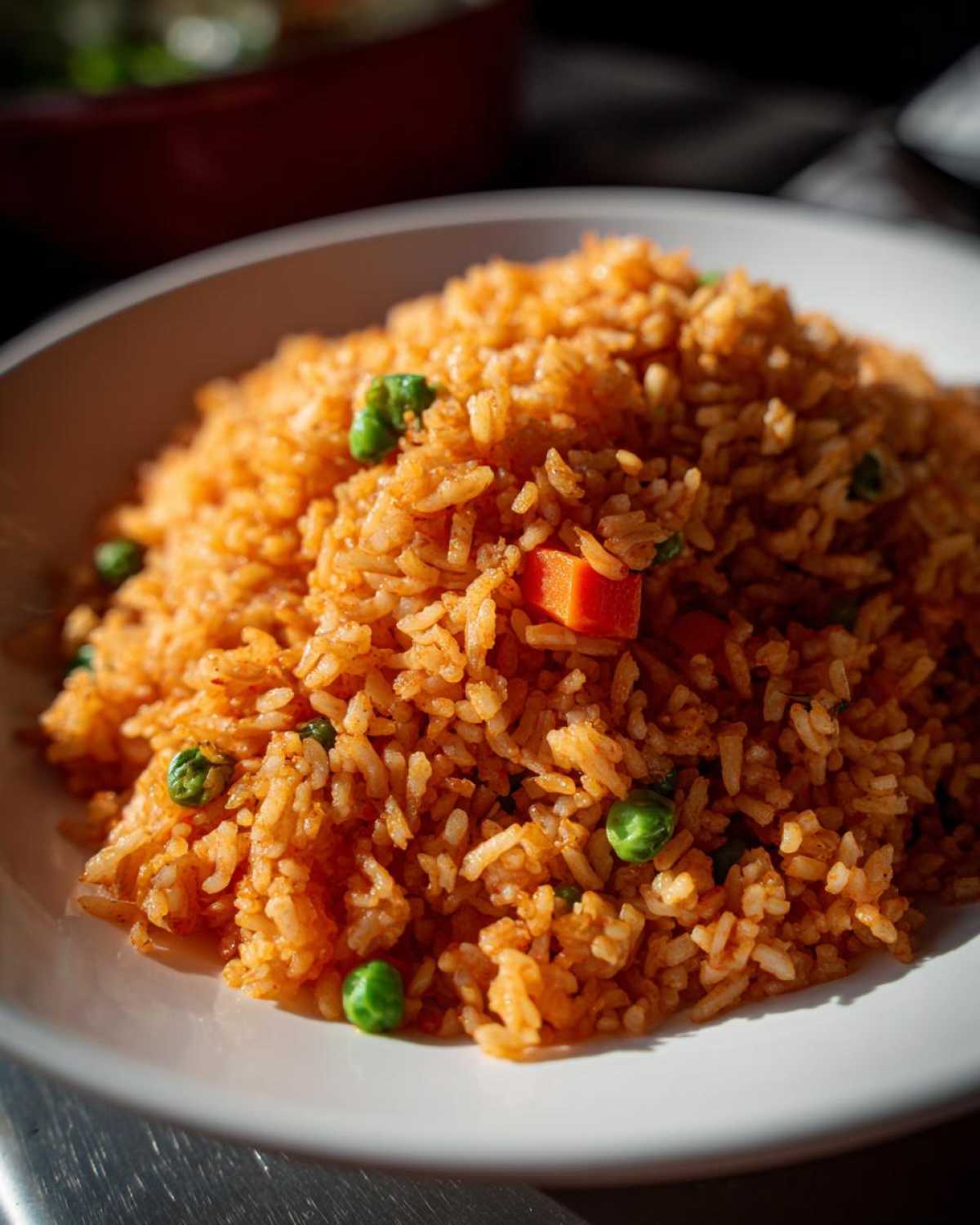 Close-up of a generous serving of vibrant orange Mexican rice recipe mixed with bright green peas and diced carrots.