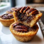 Close-up of two stacked mini pecan pies showing the gooey brown sugar filling and whole pecan topping.