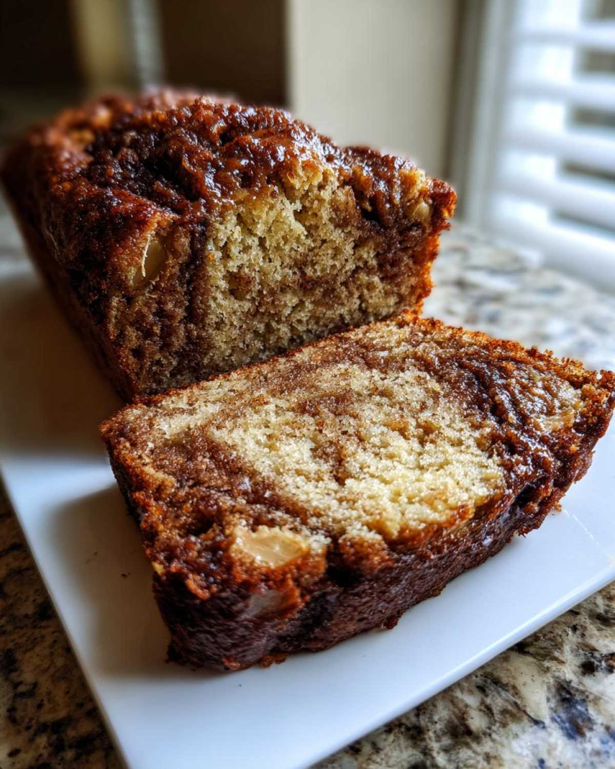 A close-up of moist apple bread, sliced to show the tender crumb and rich cinnamon swirl.