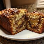 Cross-section of a moist apple bread loaf showing chunks of apple and cinnamon swirl.