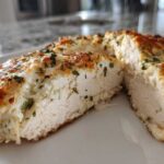 Cross-section view of juicy baked ranch chicken breast topped with melted cheese and herbs.