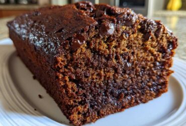 Close-up of a moist slice of rich, dark chocolate banana bread studded with melted chocolate chips.