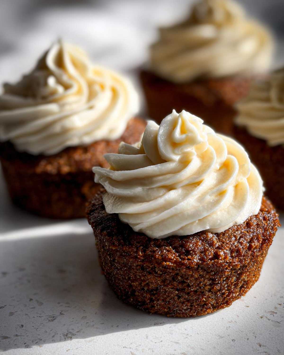 Close-up of a moist gingerbread cupcake topped with a swirl of cream cheese frosting.